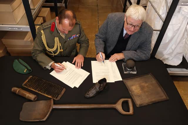 Member of staff from The National Museum of Royal Navy and Brigadier Jock Fraser MBE ADC signing the ‘deed of gift’ document.