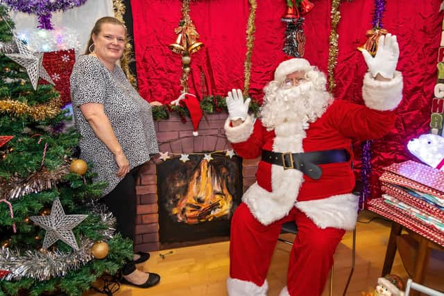 Event organiser Michelle Maquire with Santa (Mike Jerome) in front of the fireplace mural painted by Doug Cole. Picture: Mike Cooter (261121)