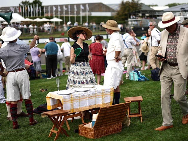 People wearing period clothing attend the opening day of Goodwood Revival at the Goodwood Motor Circuit in Chichester on September 8, 2023. The only historic motor race meeting to be staged entirely in a period theme, Goodwood Revival is an immersive celebration of iconic cars and fashion.