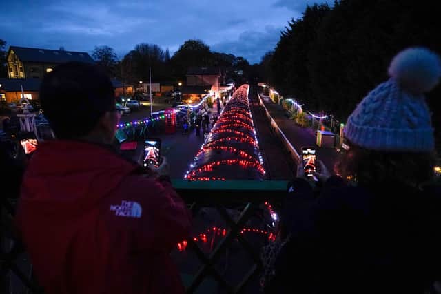 People view a Steam Illuminations train, a light show on and in a steam train, consisting of thousands of fully controllable colour mixing LED lights, as it stops at Alresford station on the Watercress Line in Hampshire, which forms part of their Christmas programme of events. Picture date: Friday November 12, 2021. PA Photo. Photo credit should read: Andrew Matthews/PA Wire
                                   