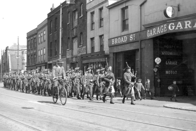 A Scottish regiment march along Broad Street, Old Portsmouth. Seen marching  ‘at ease’ can be seen soldiers of a Scottish regiment. Year unknown