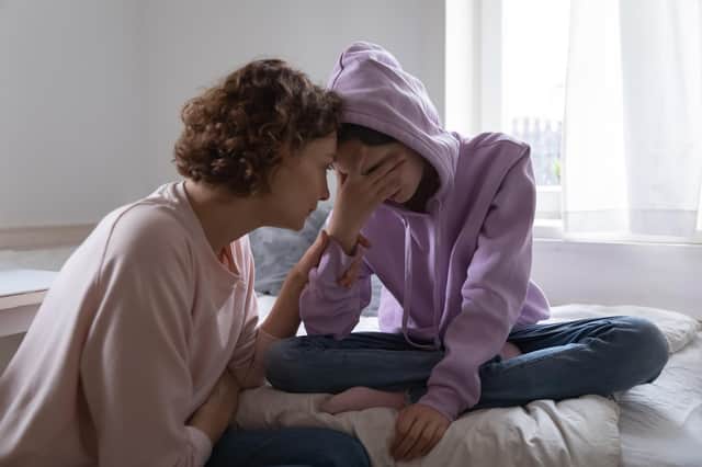 Worried mum comforting her depressed teenaged daughter.