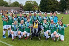 Will Stubbs holds the trophy and poses in a Moneyfields Women team picture after the team's final win over Abingdon.