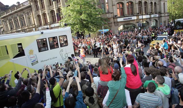 The Olympic Torch heads into the city centre watched by a huge crowd.