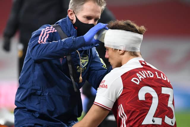 David Luiz of Arsenal receives treatment from physio Jordan Reece for a head injury during the Premier League match last November. Photo by David Price/Arsenal FC via Getty Images.