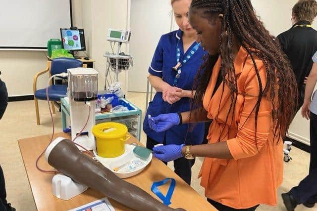 One of the students learning how to take fake blood from an artificial arm 