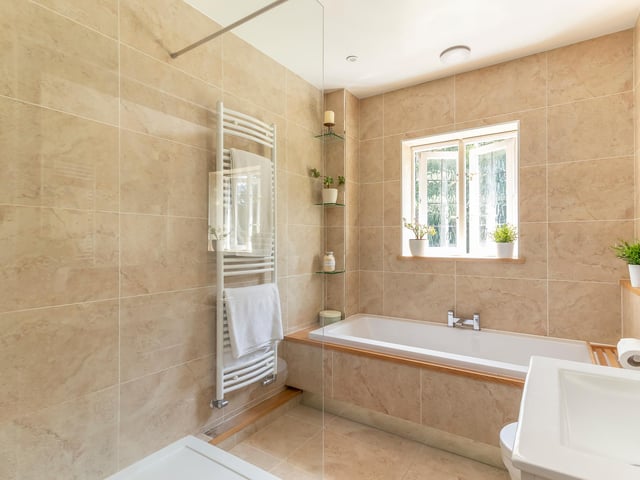 There are four bathrooms in total, including a luxurious en-suite to the main bedroom, two further bathrooms serving the remaining bedrooms, and a large shower room with marble tiling.