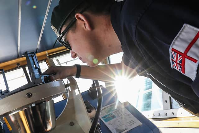 Sub Lieutenant Alex Mothersele takes a bearing on the bridge of HMS Protector during Operational Sea Training.