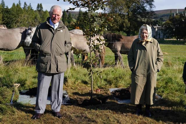 Queen Elizabeth II and Prince of Wales, as he was at the time, with a tree they planted at the Balmoral Cricket Pavilion to mark the start of the official planting season for the Queen's Green Canopy (QGC). Picture date: Friday October 1, 2021.