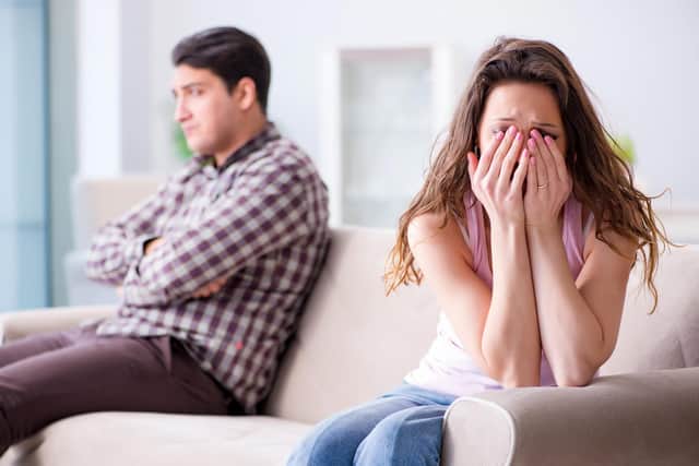A woman is pictured crying on a sofa. Picture is posed by models.