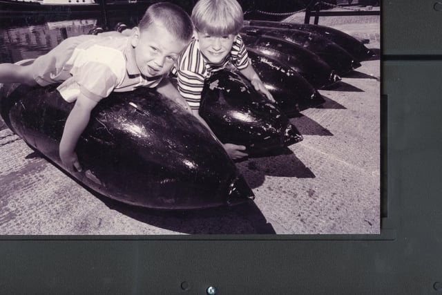 George Ayles (3), left and his friend Rory Jones (7) both from Southsea, take a rest on a row of 1000lb bombs laying in the dockside near on of the historic boathouses, 1995. The News PP5660