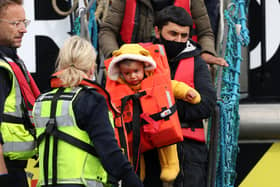 A man carries a child in a life jacket as they arrive at Dover Marina after being picked up by the border force on April 18, 2022 in Dover, England. Photo by Hollie Adams/Getty Images