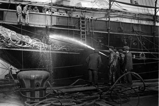 1925:  Men testing the portholes of the 'Victoria and Albert' with a hose, in preparation for her setting sail from Portsmouth.  (Photo by Hulton Archive/Getty Images)