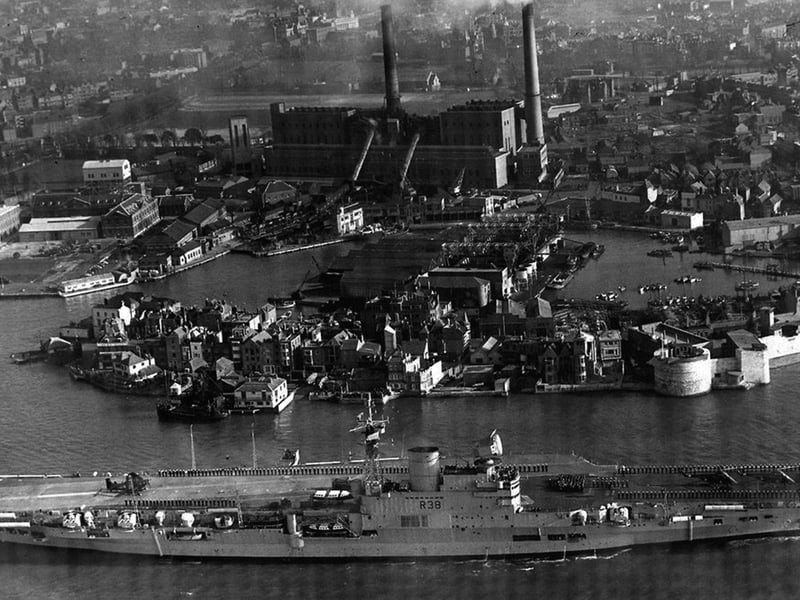 HMS Victorious leaves Portsmouth Harbour some time after 1950, as she has the angled flight deck that was fitted between 1950 and 1958.