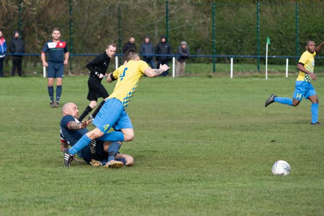 Paulsgrove's Aaron Fennemore slides in to tackle a Lyndhurst opponent. Picture: Duncan Shepherd