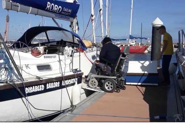 A member of the Disabled Sailors Association is helped onto one of the group's specially adapted boats.