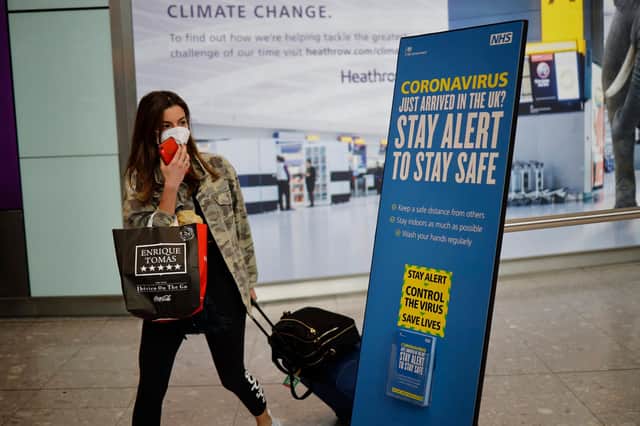 A newly arrived passenger wearing a face mask as a precaution against the novel coronavirus walks past a sign at Heathrow airport, west London with the British government's new 'Stay Alert' message on it.  (Photo by Tolga Akmen / AFP) (Photo by TOLGA AKMEN/AFP via Getty Images)