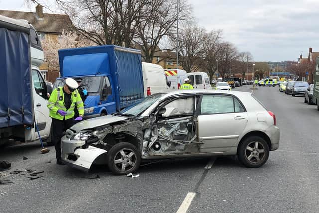 A car crashed in Northern Parade, Hilsea, leaving one person with chest injuries. Pictured: an officer inspects the damaged vehicle. Photo: Tom Cotterill