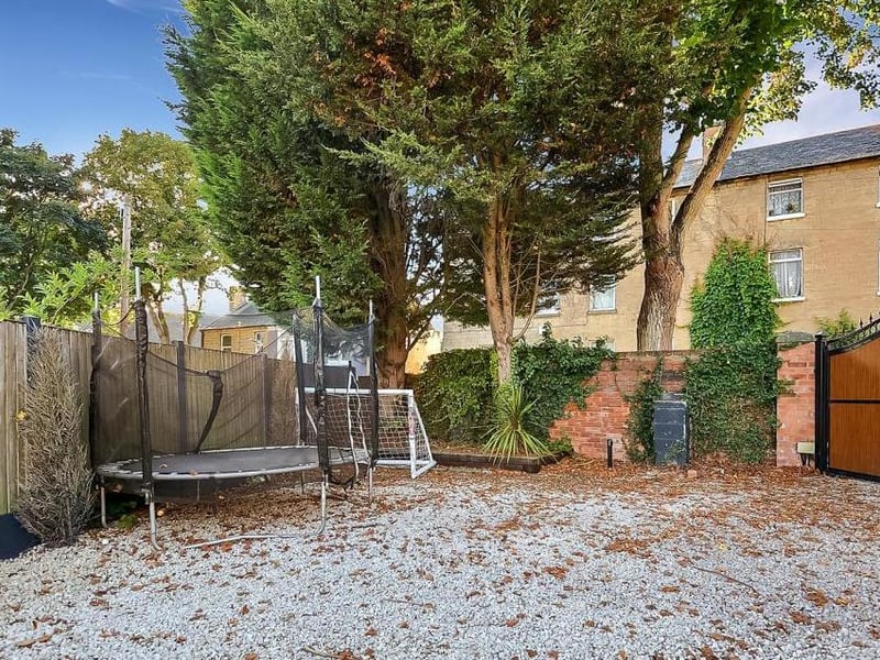 The far end of the back garden, where there is a parking area. Access is via the electric gates to the right.