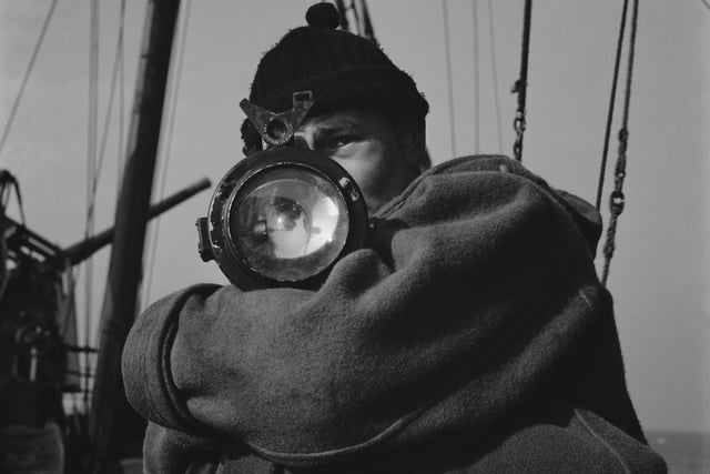 A crew member of a Royal Navy minesweeper with a handheld Aldis Brothers searchlight for Morse code signalling during World War II, March 1941.  (Photo by Horace Abrahams/Keystone Features/Hulton Archive/Getty Images)