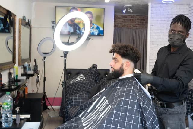 August Joseph John,owner of the Life Changer Trims barbershop cutting a client's hair in his barber shop. Picture by Mable Nsingo