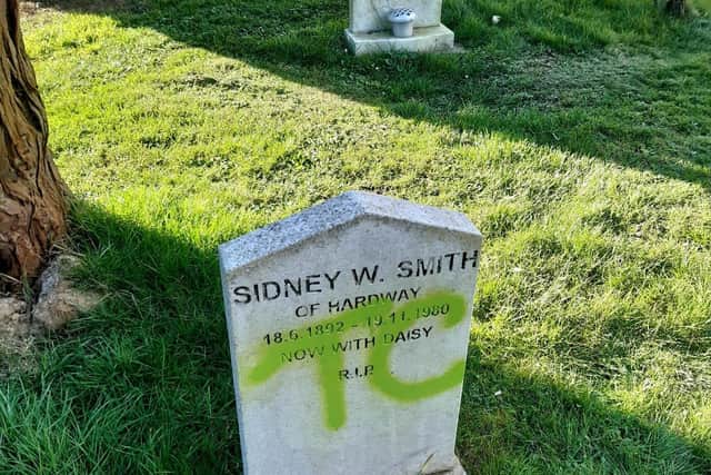 A gravestone graffitied with the letters TC.