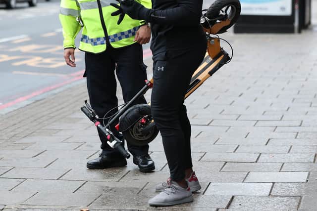 An e-scooter rider is stopped by a police officer