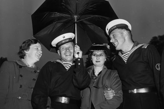 13th June 1953:  Rose Lamb (left) and Betty Brickwood share an umbrella with Victor Kapovitch (2nd left) and Vladimir Michicovitch of the Russian Navy, in Portsmouth for the Coronation Naval Review.  (Photo by George W. Hales/Fox Photos/Getty Images)