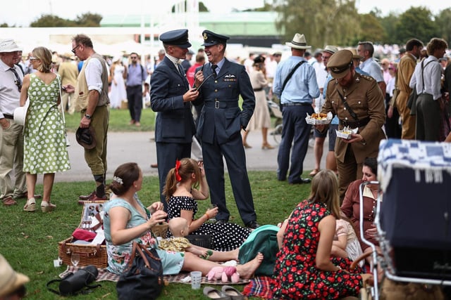 People wearing period clothing attend the opening day of Goodwood Revival at the Goodwood Motor Circuit in Chichester on September 8, 2023. The only historic motor race meeting to be staged entirely in a period theme, Goodwood Revival is an immersive celebration of iconic cars and fashion. (Photo by HENRY NICHOLLS / AFP) (Photo by HENRY NICHOLLS/AFP via Getty Images)