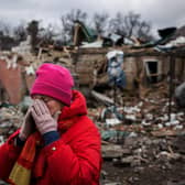 Irina Moprezova, 54, reacts in front of a house that was damaged in an aerial bombing in the city of Irpin, northwest of Kyiv on March 13, 2022.  (Photo by DIMITAR DILKOFF/AFP via Getty Images)