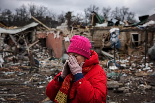 Irina Moprezova, 54, reacts in front of a house that was damaged in an aerial bombing in the city of Irpin, northwest of Kyiv on March 13, 2022.  (Photo by DIMITAR DILKOFF/AFP via Getty Images)
