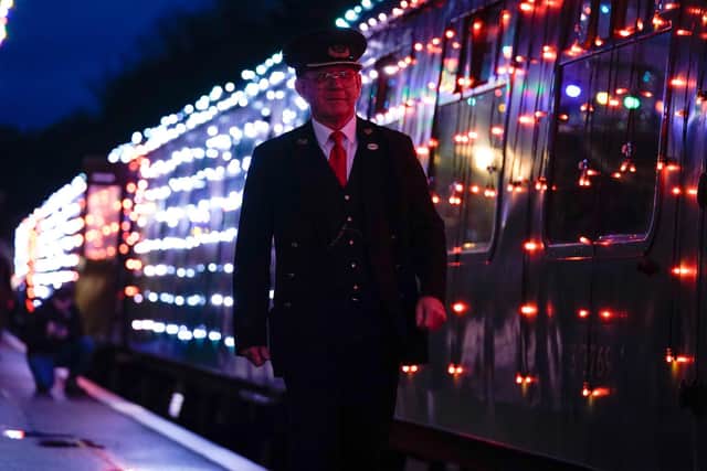 A guard walks past a Steam Illuminations train, a light show on and in a steam train, consisting of thousands of fully controllable colour mixing LED lights, as it stops at Alresford station on the Watercress Line in Hampshire, which forms part of their Christmas programme of events. Picture date: Friday November 12, 2021. PA Photo. Photo credit should read: Andrew Matthews/PA Wire