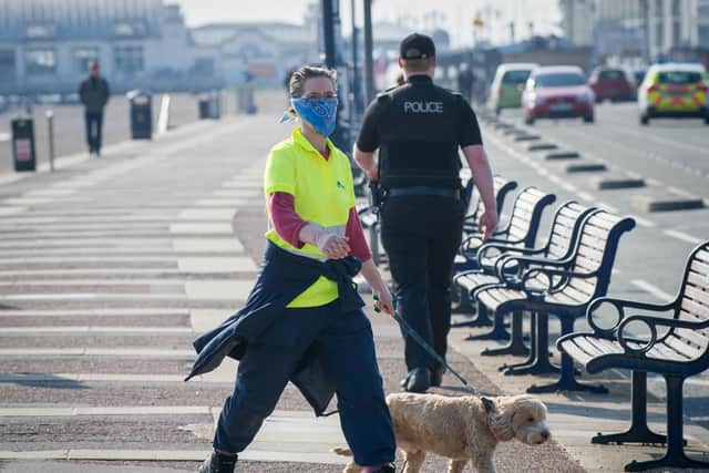 Pictured: A woman wears a mask with police in the background in Southsea on March 27 2020. Picture: Habibur Rahman
