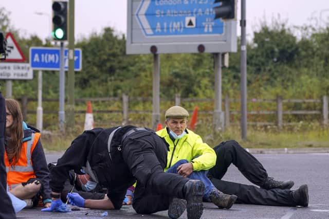 Police officers work to free protesters who had glued themselves to a slip road at Junction 4 of the A1(M), near Hatfield, where climate activists carried out a further action after demonstrations which took place last week across junctions in Kent, Essex, Hertfordshire and Surrey.  Picture date: Monday September 20, 2021. Steve Parsons/PA Wire