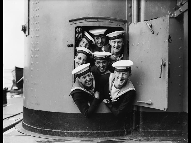 September 1928:  A group of sailors trying to squeeze out of a small door aboard the HMS Hood during naval manoeuvres.  (Photo by Fox Photos/Getty Images)