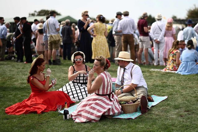 People wearing period clothing attend the opening day of Goodwood Revival at the Goodwood Motor Circuit in Chichester on September 8, 2023. The only historic motor race meeting to be staged entirely in a period theme, Goodwood Revival is an immersive celebration of iconic cars and fashion.