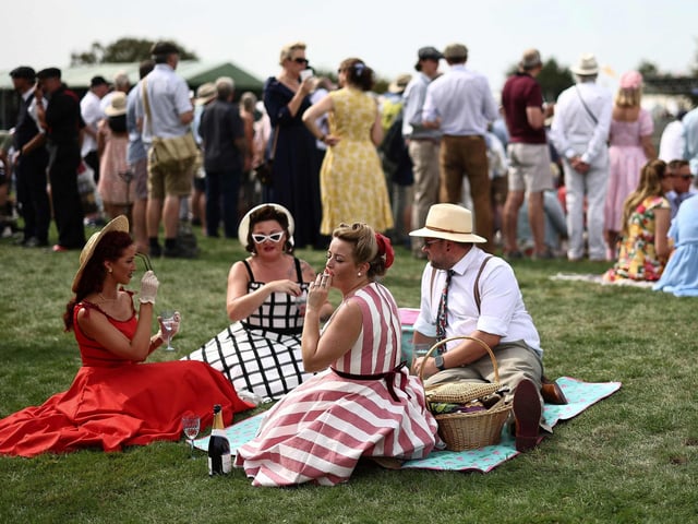 People wearing period clothing attend the opening day of Goodwood Revival at the Goodwood Motor Circuit in Chichester on September 8, 2023. The only historic motor race meeting to be staged entirely in a period theme, Goodwood Revival is an immersive celebration of iconic cars and fashion.
