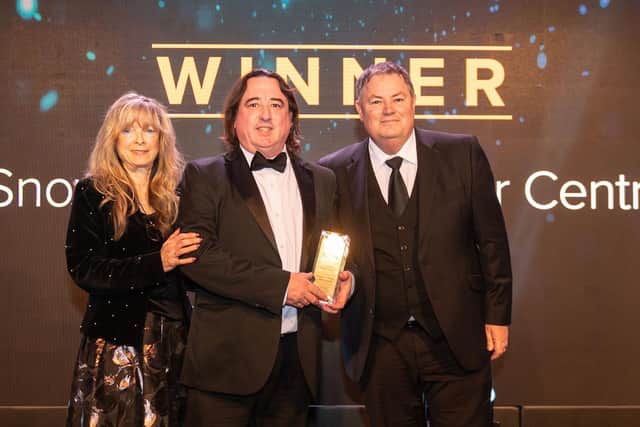 Dan Bush, centre, receives the award for Snows Accident Repair Centre from awards night compere Mike Brewer, right, and Michelle Brewer, representing category sponsor OnCue Communications.