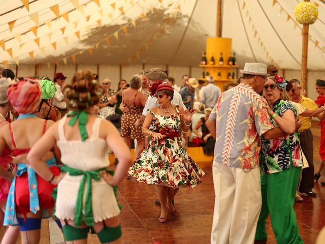People wearing period clothing attend the opening day of Goodwood Revival at the Goodwood Motor Circuit in Chichester on September 8, 2023. The only historic motor race meeting to be staged entirely in a period theme, Goodwood Revival is an immersive celebration of iconic cars and fashion. (Photo by HENRY NICHOLLS / AFP) (Photo by HENRY NICHOLLS/AFP via Getty Images)