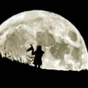 A person holding a witch's hat watches the Blue Moon rise over Castle Hill in Huddersfield, the last full moon to fall on Halloween until 2039.
