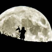 A person holding a witch's hat watches the Blue Moon rise over Castle Hill in Huddersfield, the last full moon to fall on Halloween until 2039.