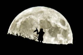 A person holding a witch's hat watches the Blue Moon rise over Castle Hill in Huddersfield, the last full moon to fall on Halloween until 2039.