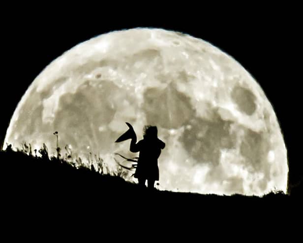 A person holding a witch's hat watches the Blue Moon rise over Castle Hill in Huddersfield, the last full moon to fall on Halloween until 2039.