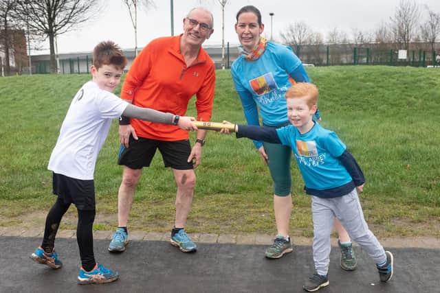 Vicki and Owen Brunink with one of the golden batons being passed around parkruns across the country, passing it onto William Marshall and Mel Murray. Picture: Keith Woodland