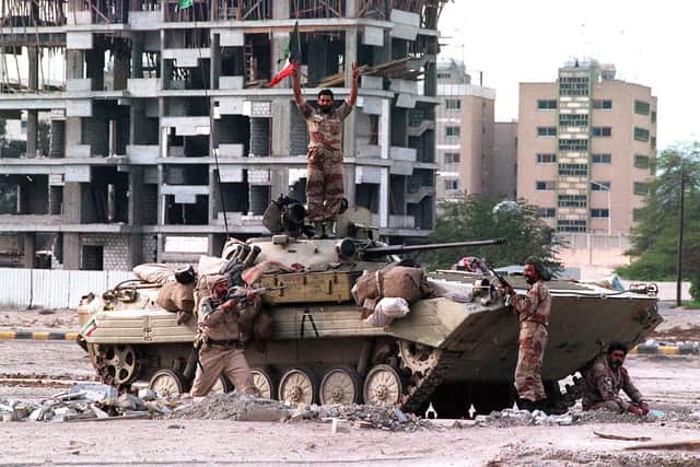 Allied soldiers with the spoils of victory - an abandoned Iraqi tank on a street corner in Kuwait City.