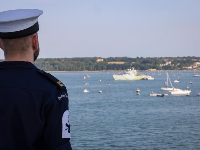 Pictured : HMS Queen Elizabeth's company lining the upper deck with HMS Tyne in the background