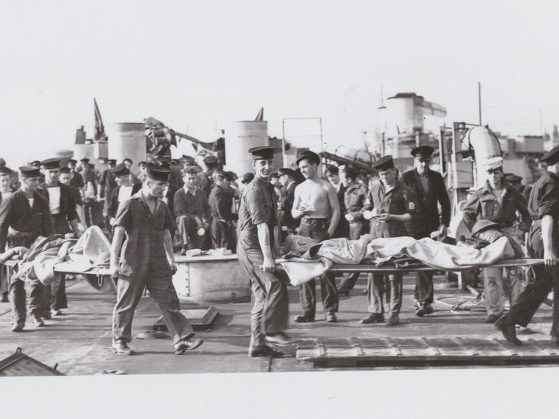 Wounded soldiers on stretchers being carried off a ship.