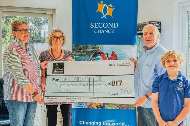 Di Lloyd (centre left) presents the cheque to Doug Hulme (centre right) supported by Clare Hulme (left).