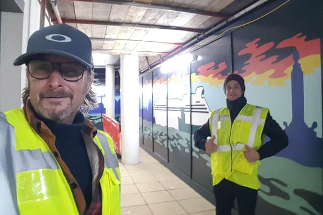 Mark Lewis and his helper completing a mural on Gosport hoardings