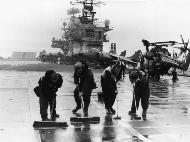 Four men scrubbing the flight deck on HMS Hermes during the Falklands conflict, May 1982. (Photo by Martin Cleaver/Pool/Getty Images)